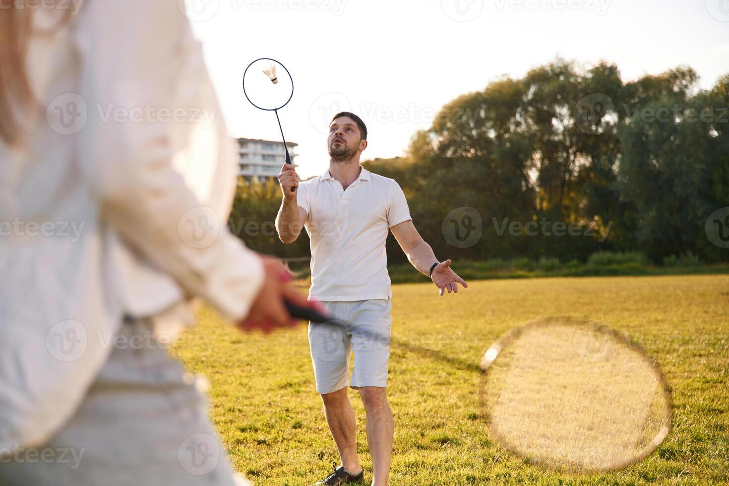 Conception of sports and ,hobby. Man with woman are playing badminton on the field photo