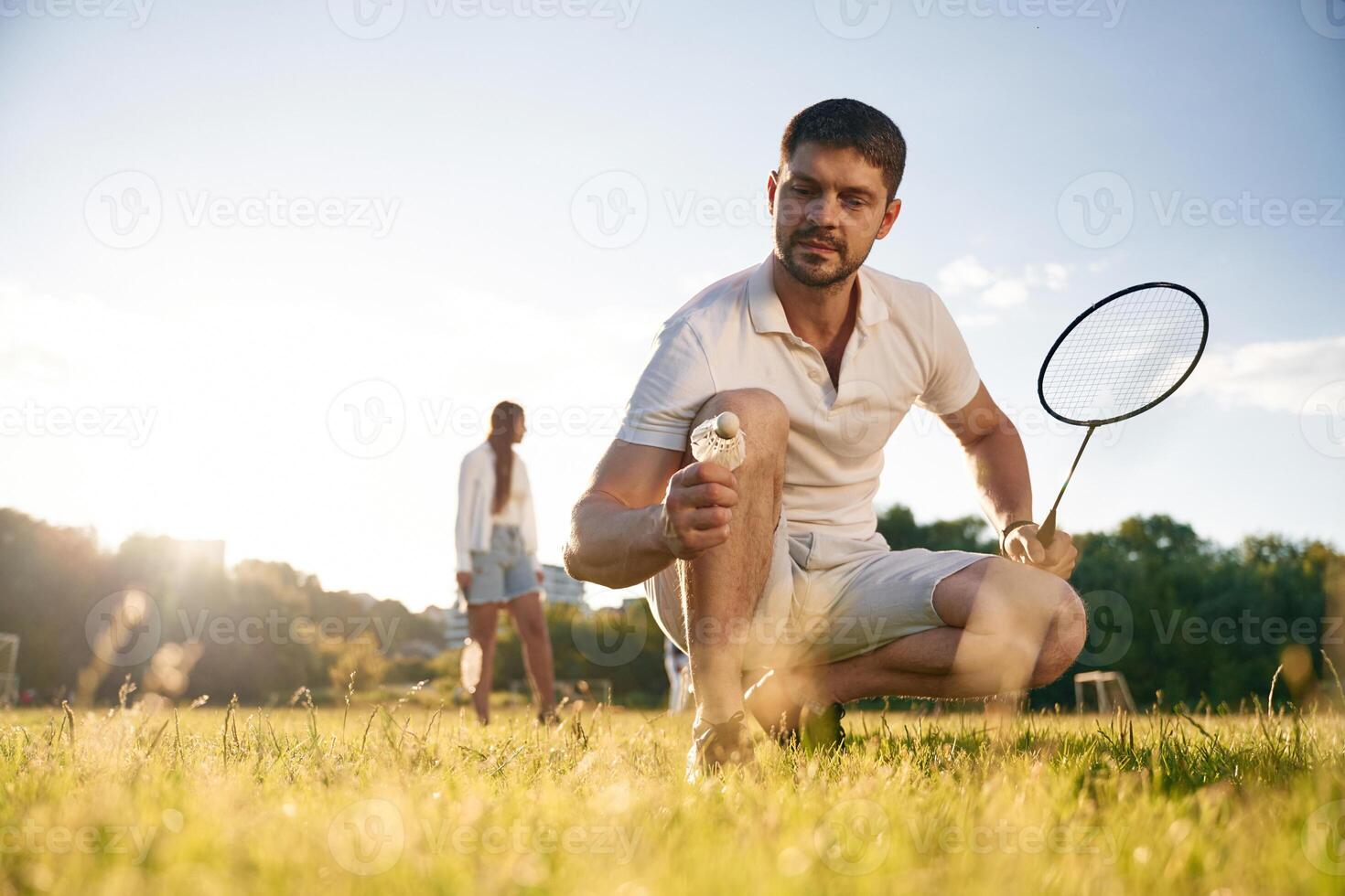 Man ,with ,,woman are playing badminton on the field photo