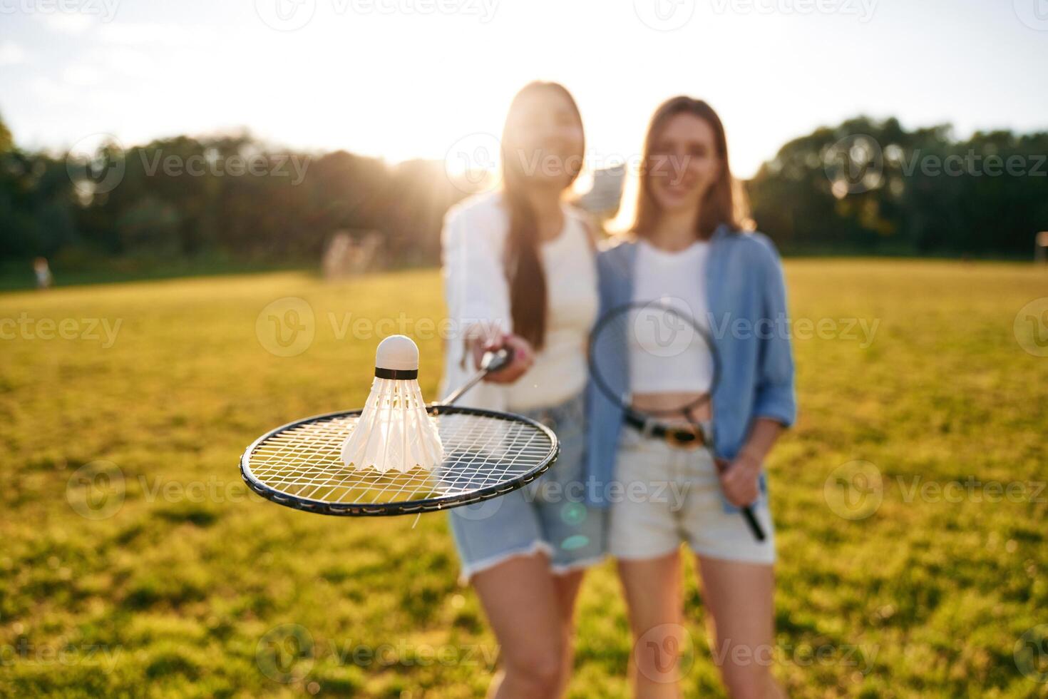 Shuttlecock is on the badminton, racket. Two women are having fun, on the field photo