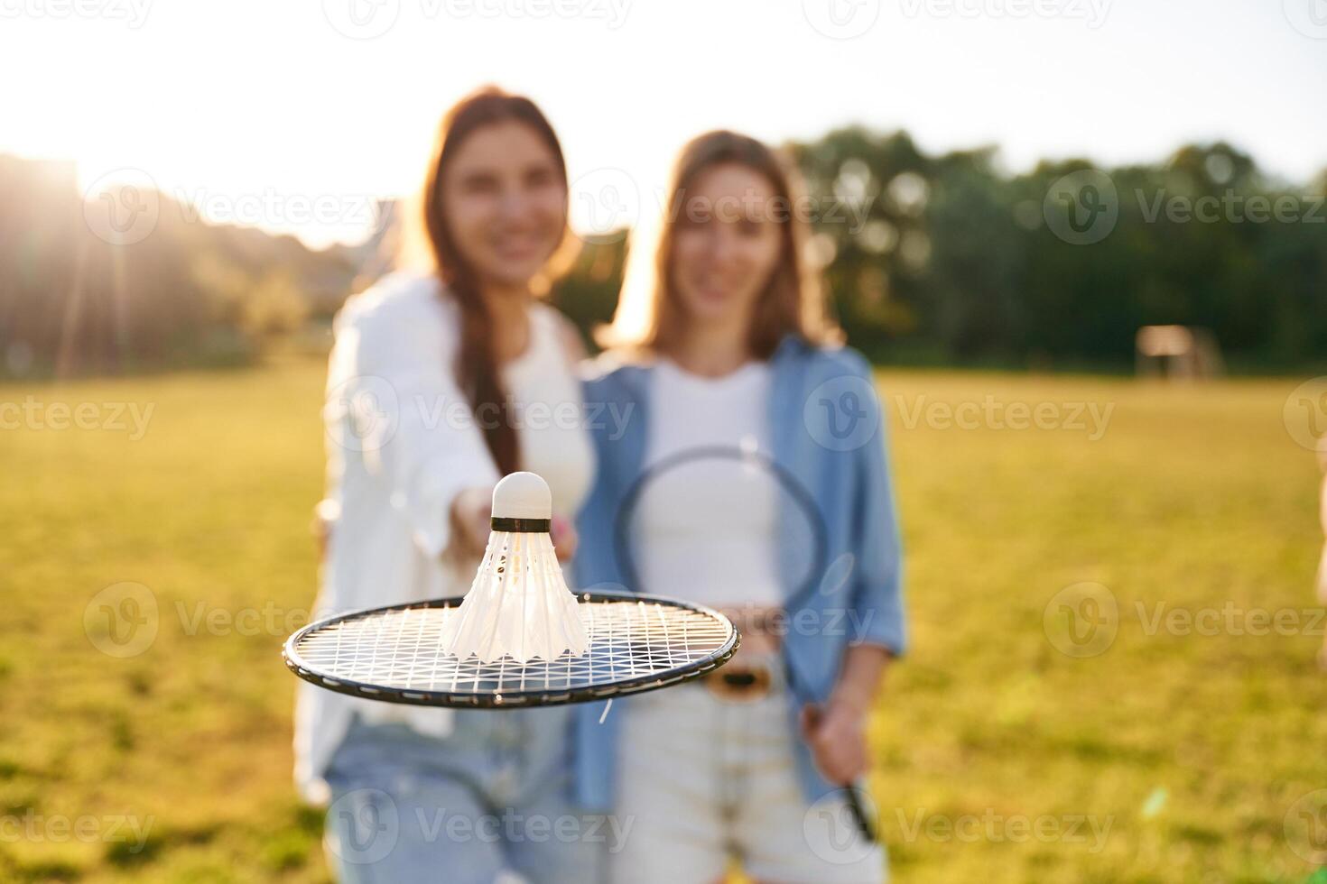 Shuttlecock is on ,the badminton racket. Two women are having fun, on the field photo