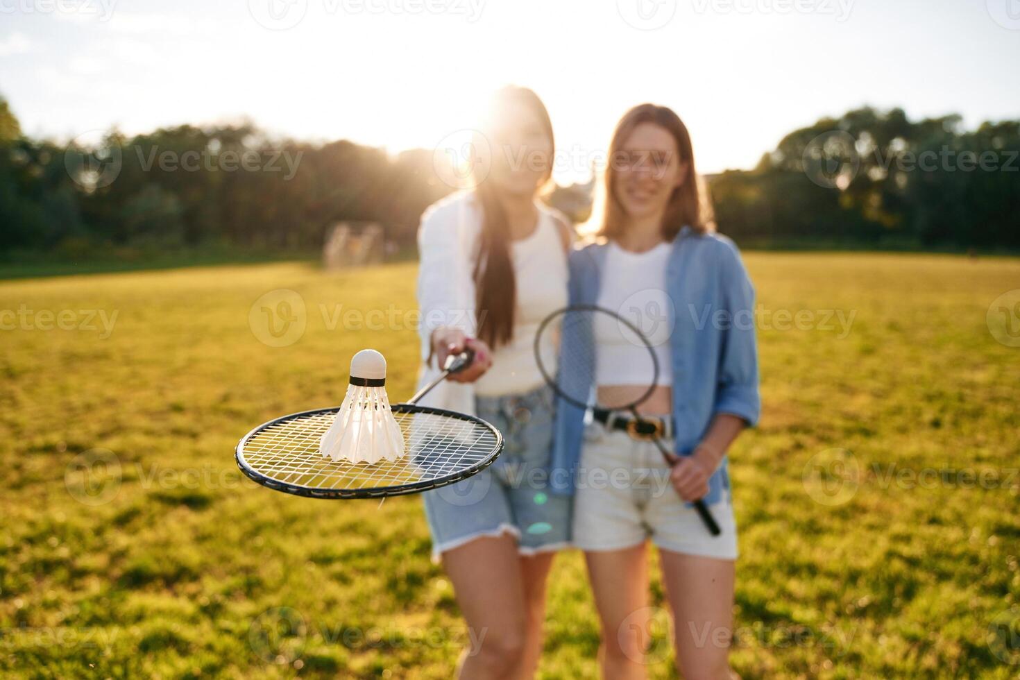 Shuttlecock is ,on the badminton racket. Two women are having fun, on the field photo