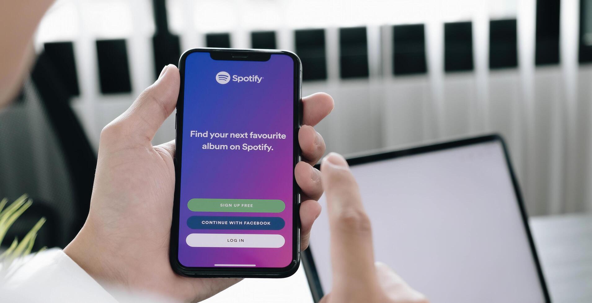 CHIANG MAI, THAILAND - JUL 28 2020. Person holding a brand new Apple iPhone XS with Spotify logo on the screen. Spotify is a popular commercial music streaming service. photo