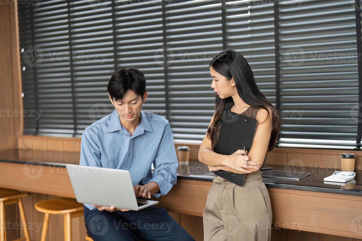 Business Consultation and Collaboration. Two young professionals discussing work-related topics in an office. photo