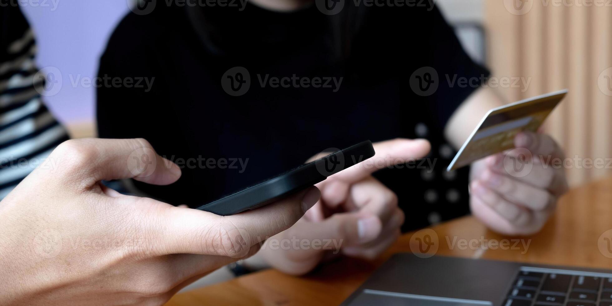 Selective focus of positive man holding smartphone while using credit card near woman photo