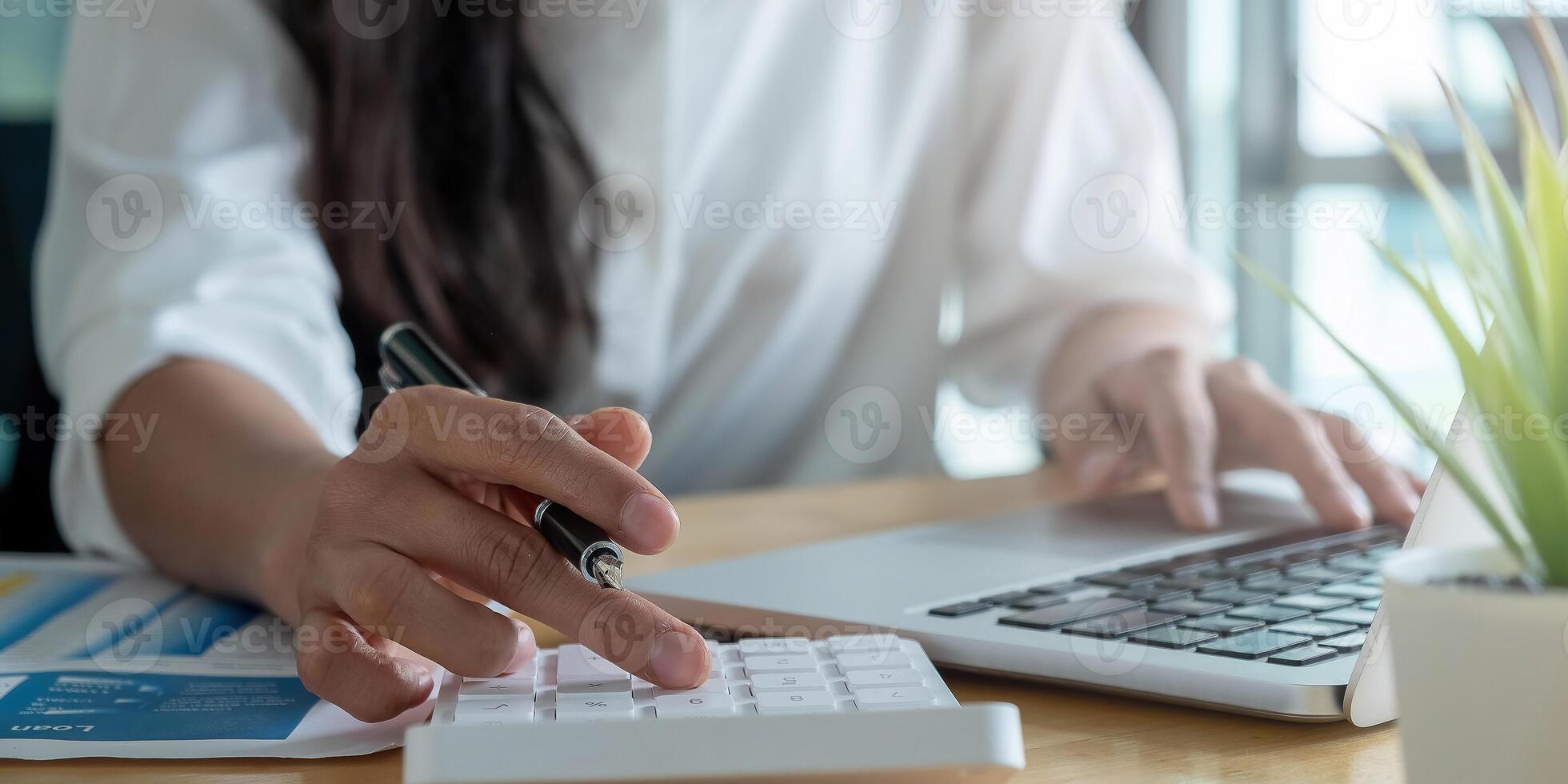 Close up Businesswoman using calculator and laptop for do math finance on wooden desk in office and business working background, tax, accounting, statistics and analytic research concept photo