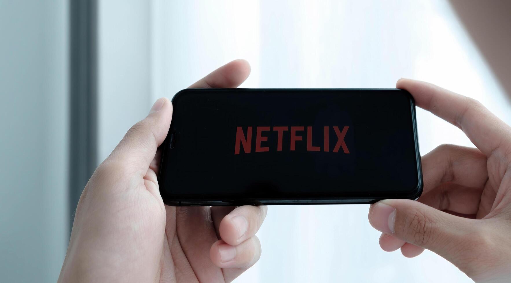 CHIANG MAI, THAILAND, MAR 25 , 2021. Woman hand holding Smart Phone with Netflix logo on Apple iPhone Xs. Netflix is a global provider of streaming movies and TV series. photo