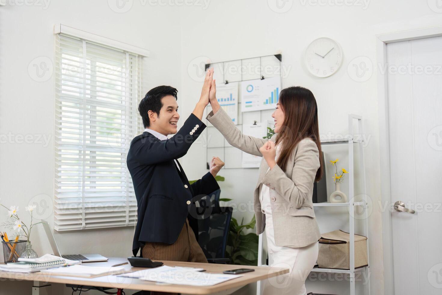 Teamwork and Achievement. Colleagues sharing a joyful moment with high fives in a modern office. photo