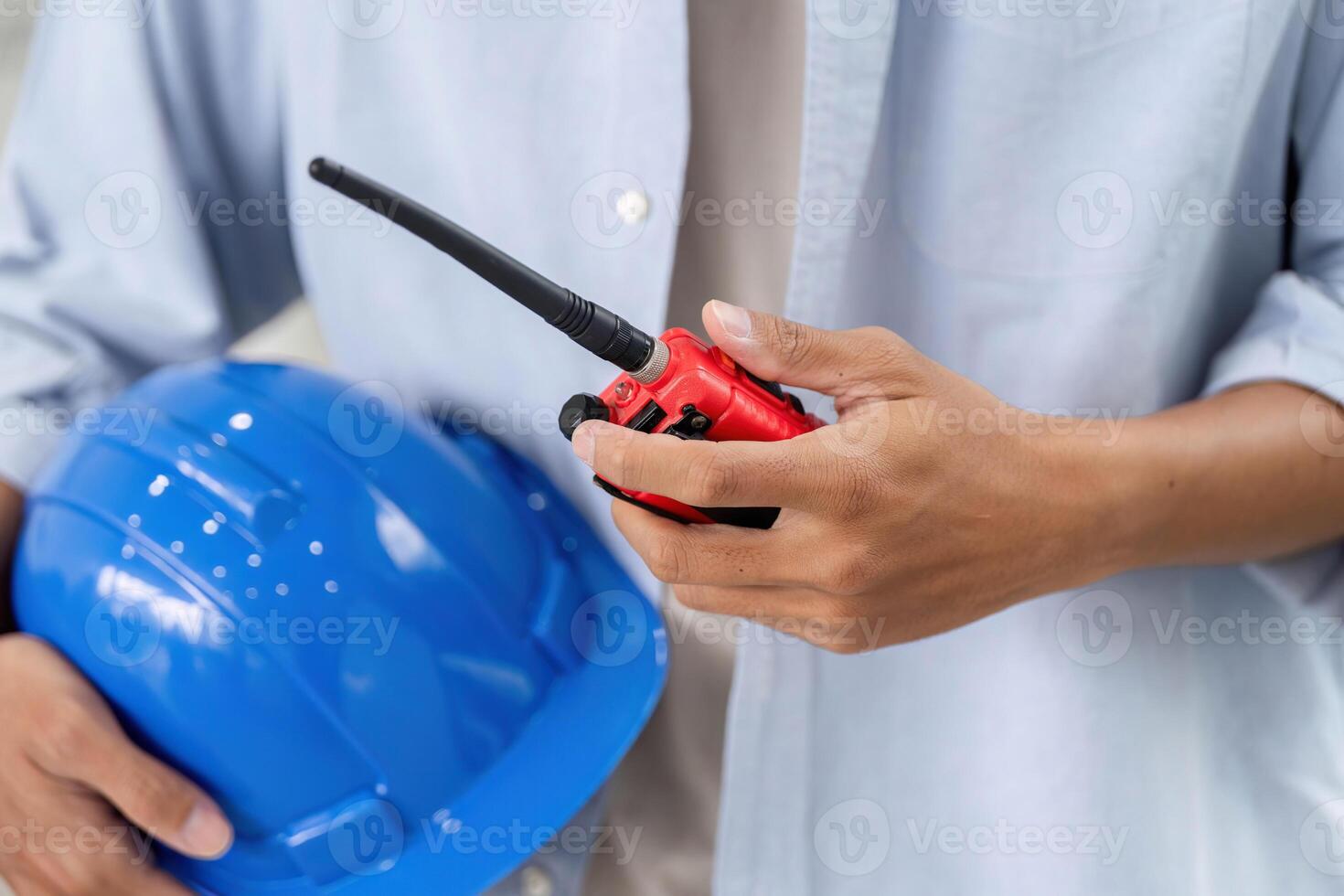 Safety and Communication in Construction. Close-up of engineer holding helmet and walkie-talkie. photo