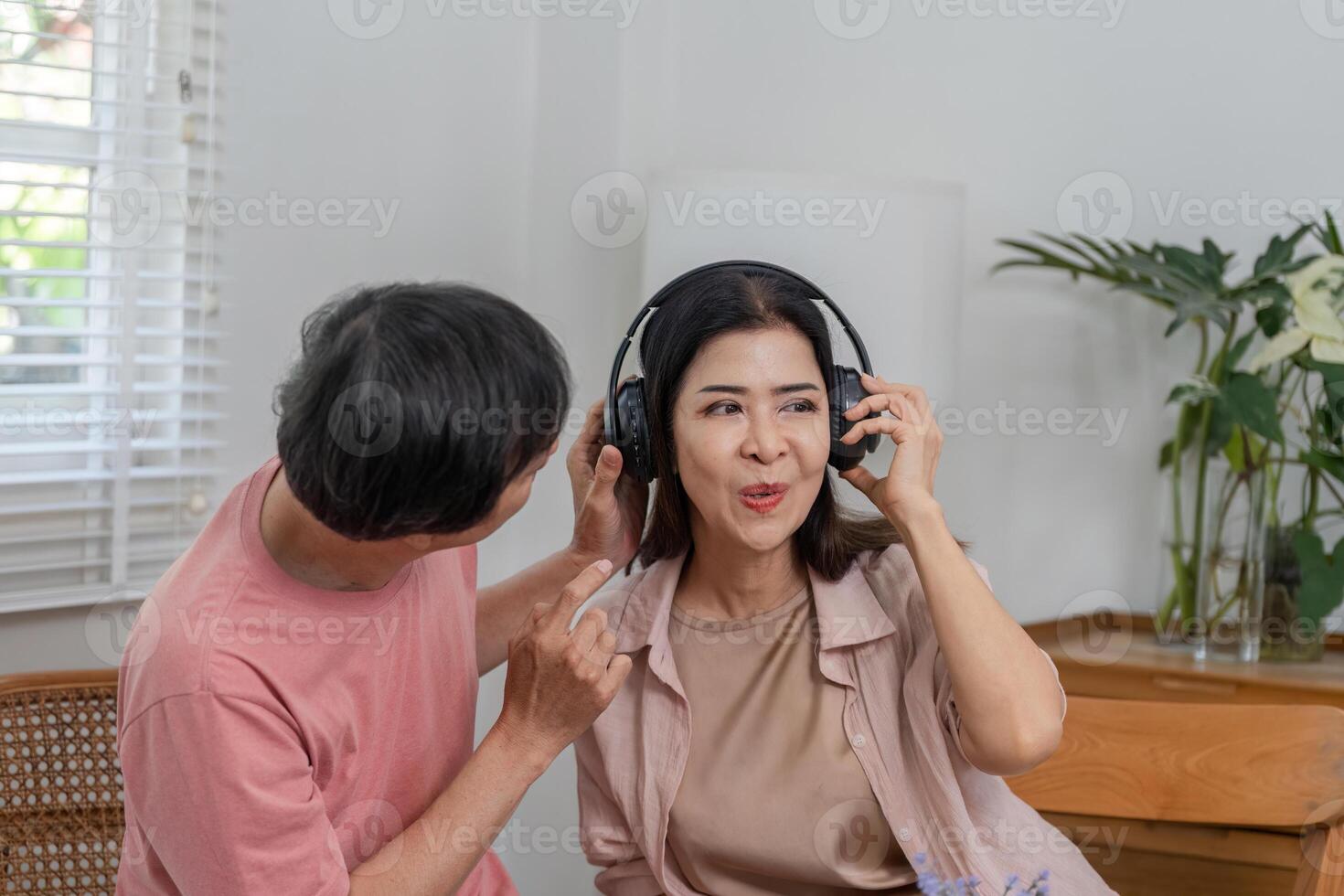 Mature couple enjoying music together with headphones at home. photo