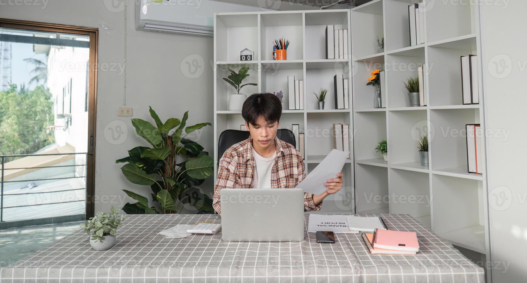 Young financial professional analyzing documents and calculating budget in a modern workspace photo