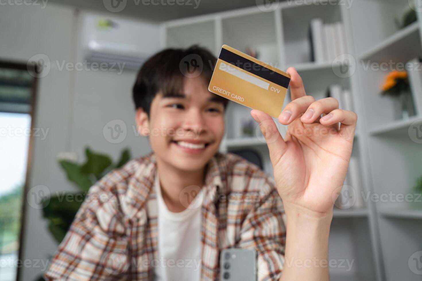Young man smiling while holding a credit card, showcasing financial empowerment and online shopping. photo