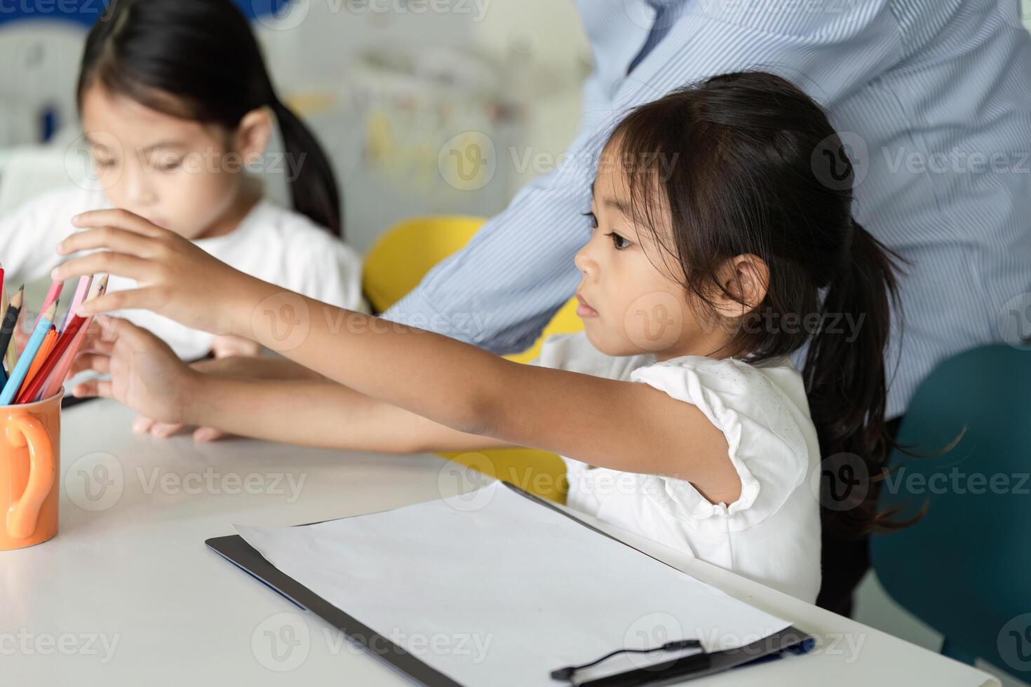 Back to School. Children reaching for colorful pencils in a classroom. photo