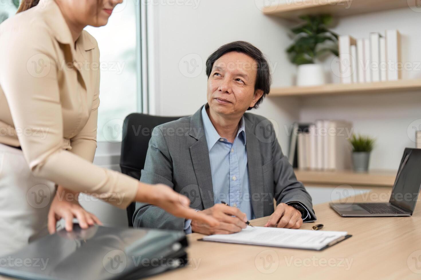 Professional Discussion and Document Review. Businessman signing paperwork during a meeting with a colleague. photo