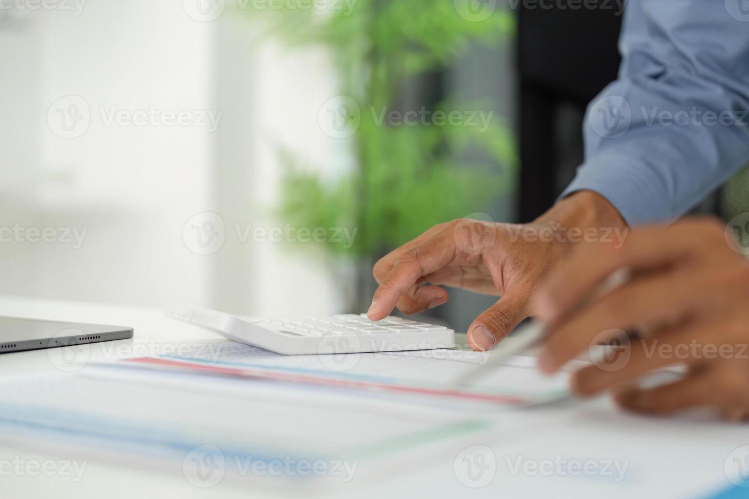 Efficient Data Entry. Professional using calculator while analyzing reports on a desk. photo