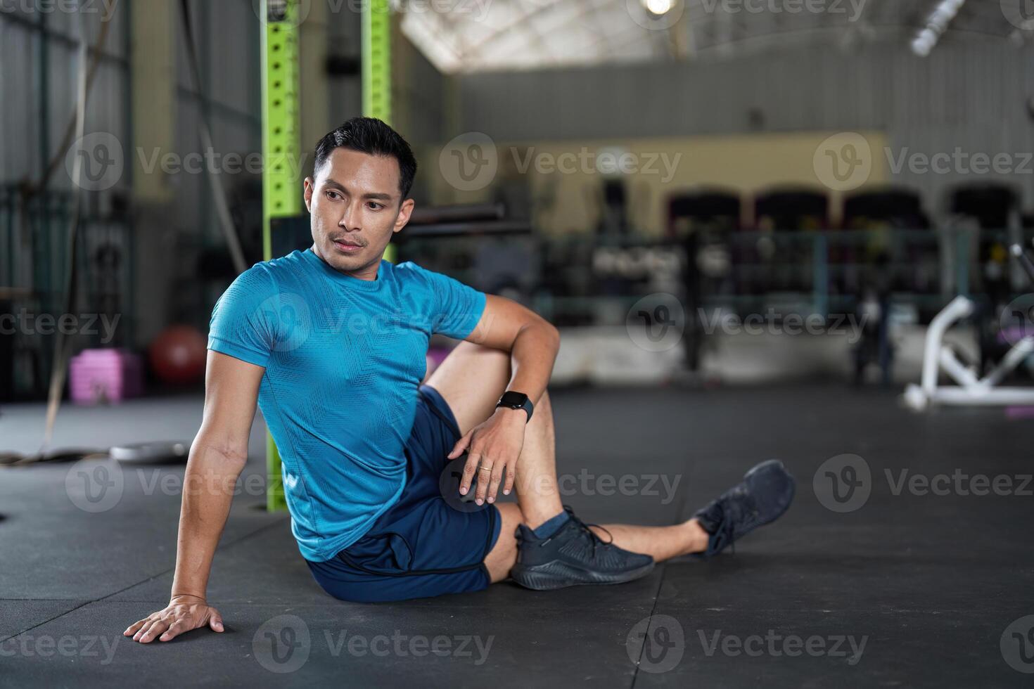 Fitness and Recovery. Man in a seated position on gym floor, preparing for stretching. photo