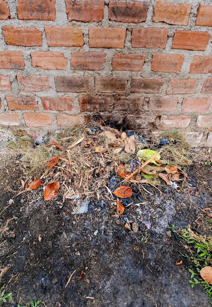 a pile of trash and leaves in front of a brick wall photo