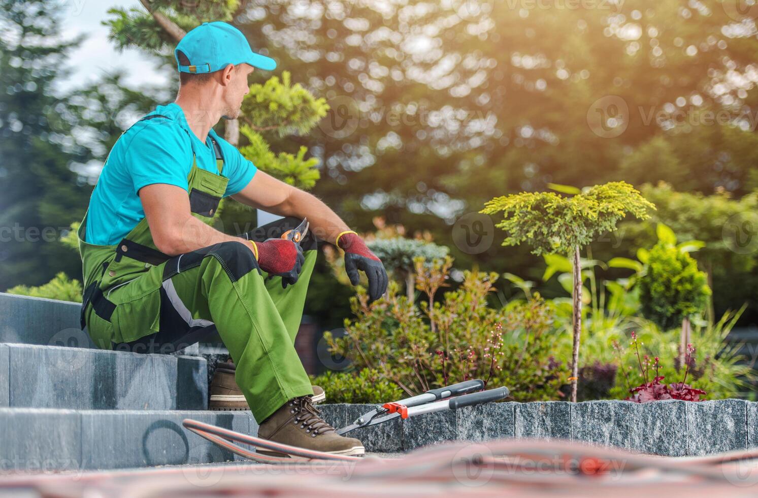 Gardener Resting While Planning Next Steps in Landscaped Garden During Sunny Afternoon in Residential Area photo