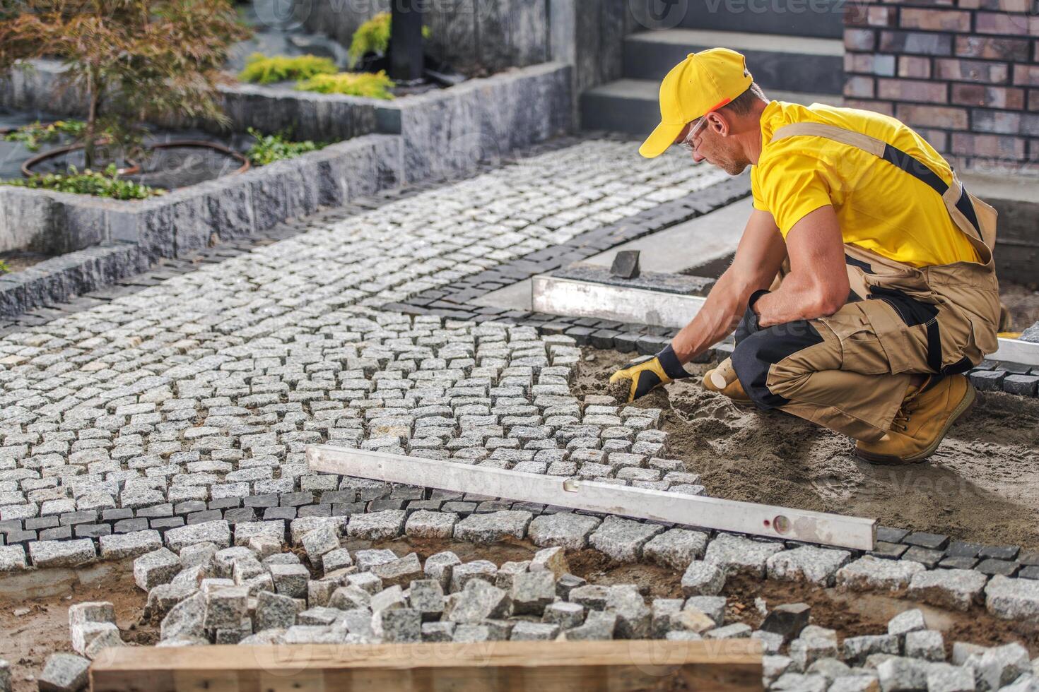 Worker Laying Cobblestones for a New Pathway in a Residential Garden During Daylight Hours photo