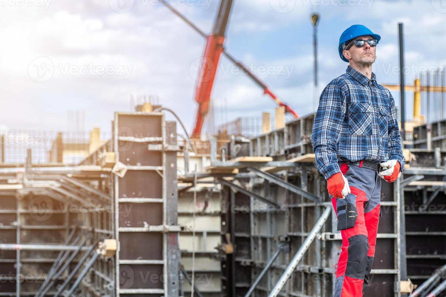 Construction Worker Overseeing Building Project While Wearing Safety Gear and Monitoring Activity at Construction Site During Daytime photo