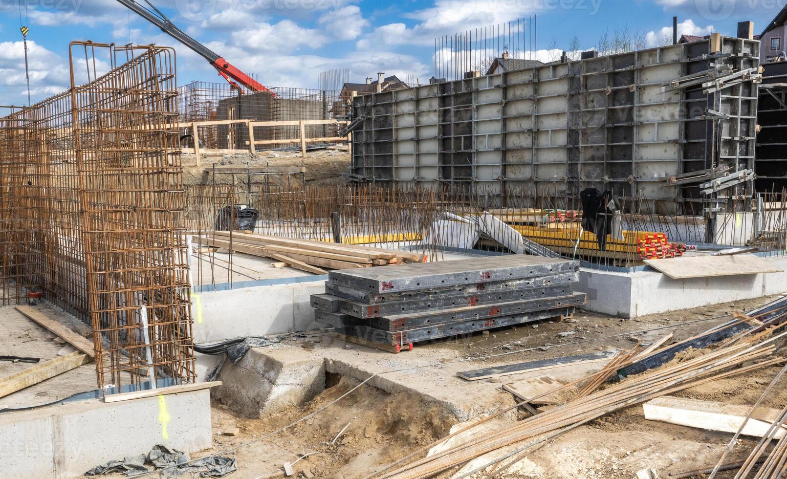 Construction Site With Foundation Work Underway in an Urban Area Surrounded by Machinery and Materials During a Clear Day photo