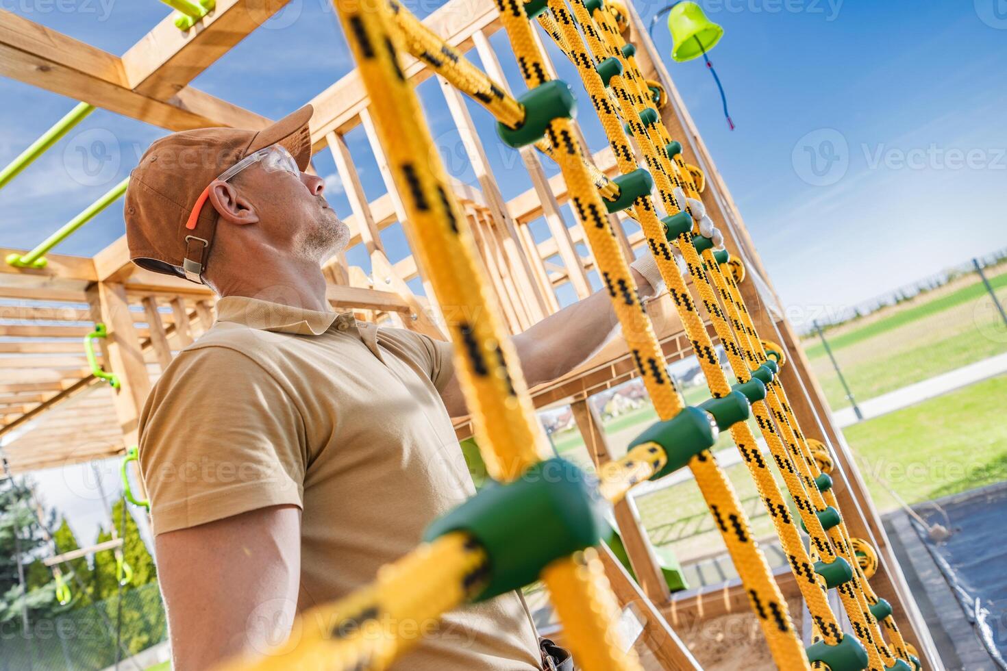 Worker Inspects Climbing Structure at Playground Construction Site in Bright Daytime photo