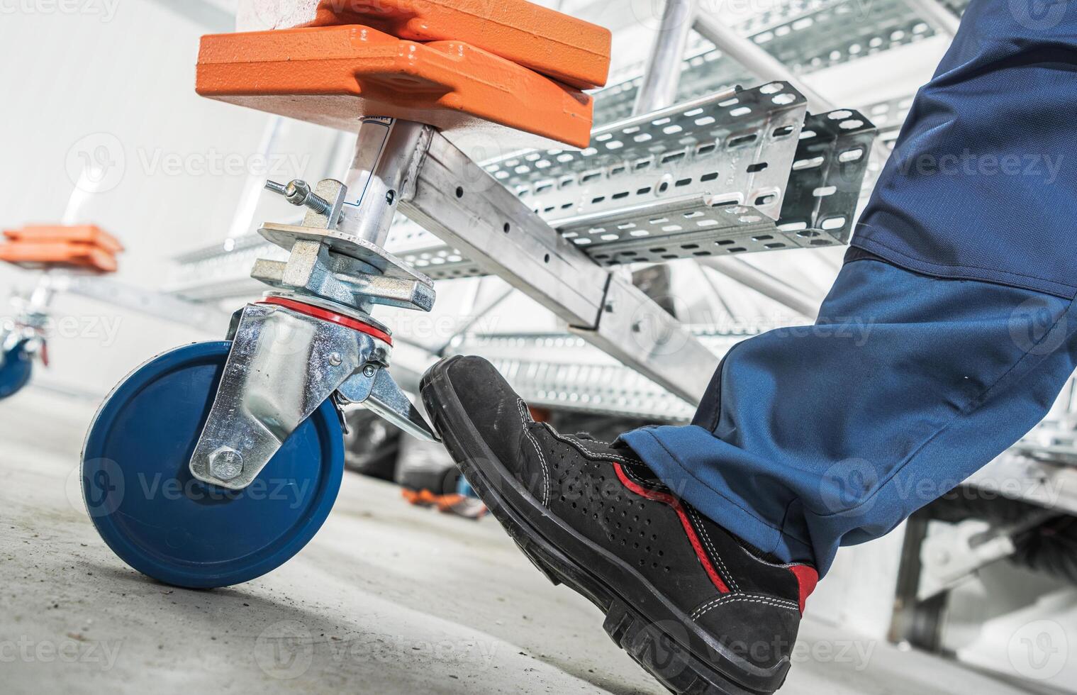 Foot Pressing Down on a Wheel Break of a Scaffolding Cart in a Construction Site photo