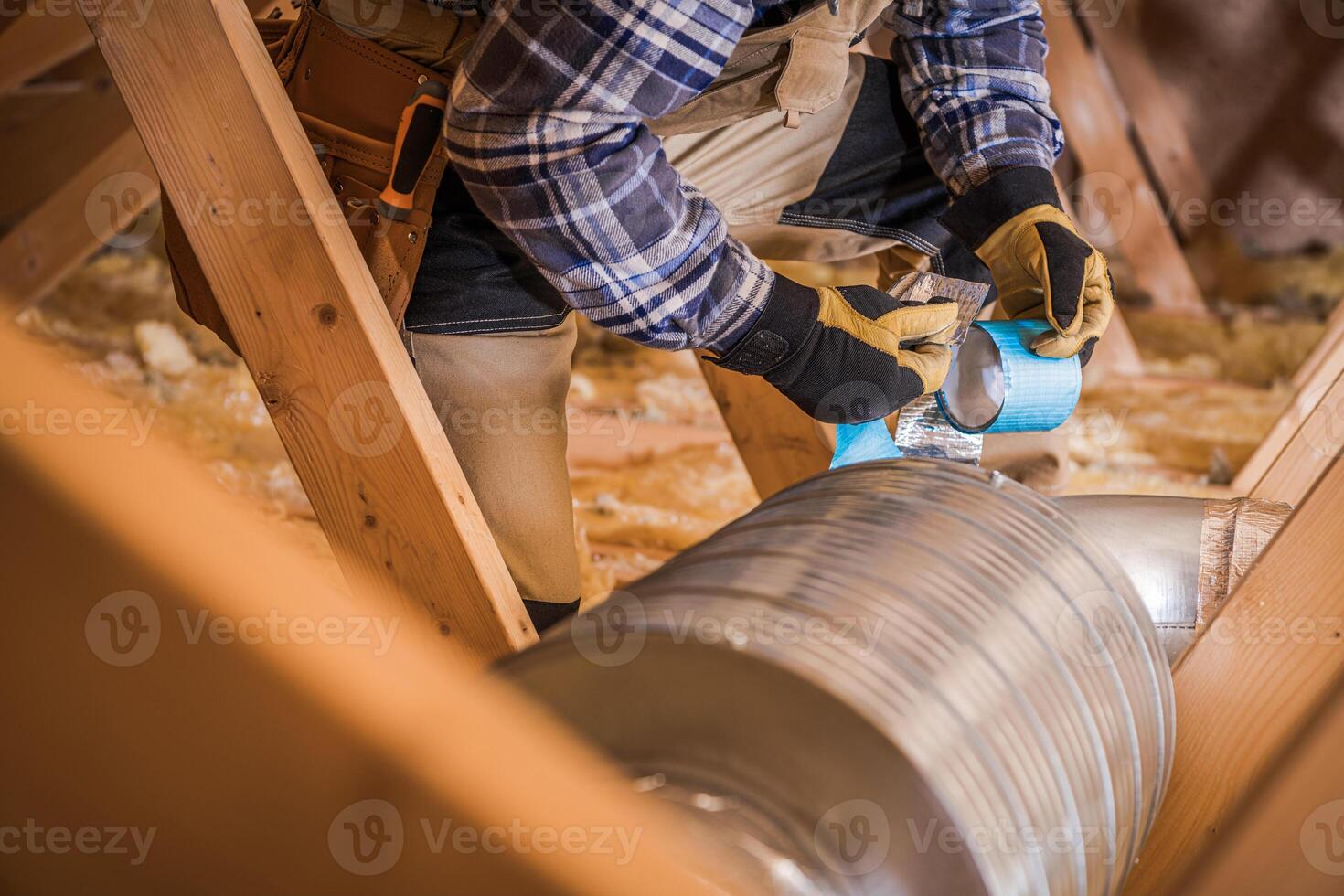 Worker Repairing Ductwork With Tape in Attic During Home Renovation Project photo