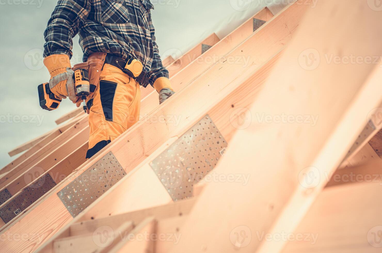 Construction Worker Using Power Tool on Roof During Daylight at a Building Site in a Residential Area photo