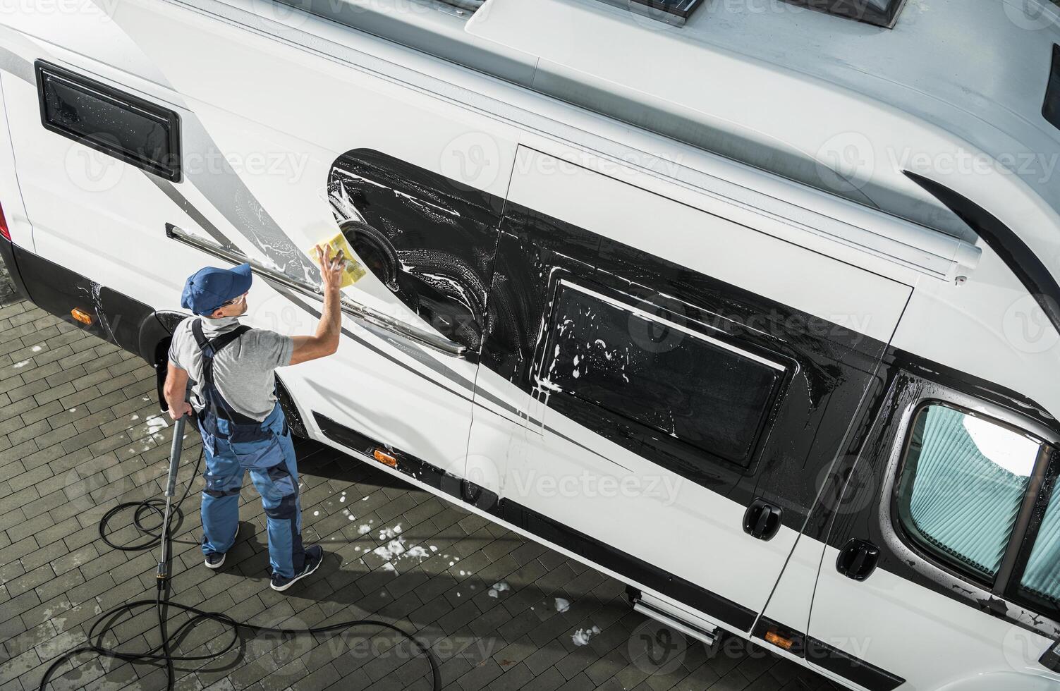 Professional Cleaning of a Recreational Vehicle Takes Place in a Driveway During Daylight Hours photo