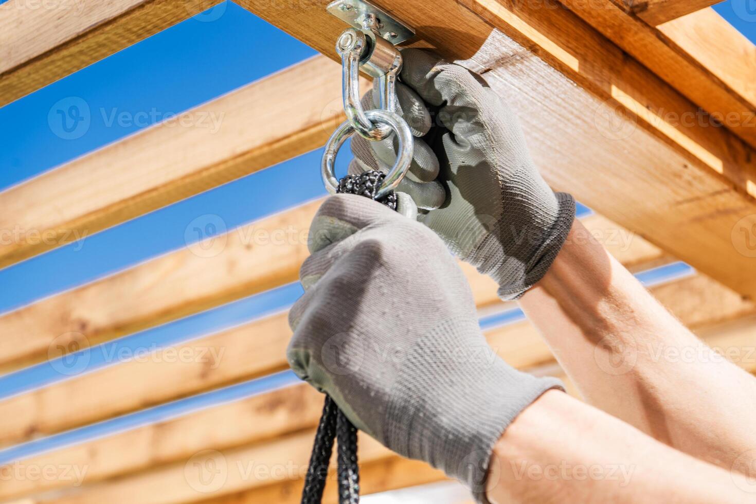 Construction Worker Adjusts Pulley System for Outdoor Shade Structure in Sunny Environment During Afternoon Hours photo