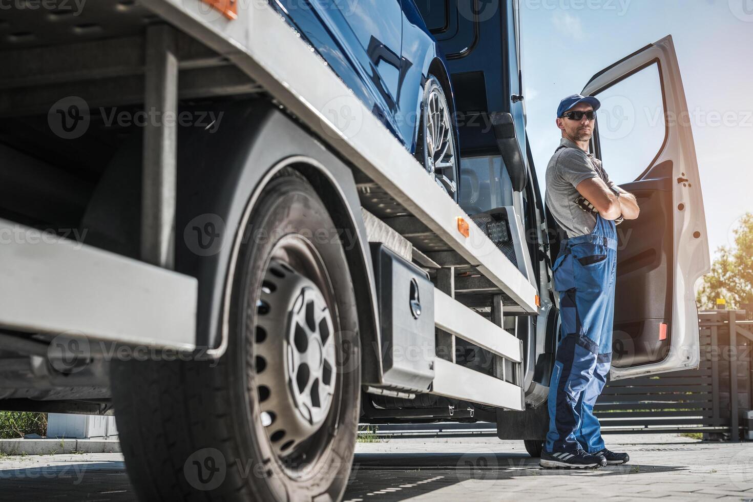 Transport Worker Loading Vehicle Onto Truck During Bright Sunny Day at Logistics Facility photo