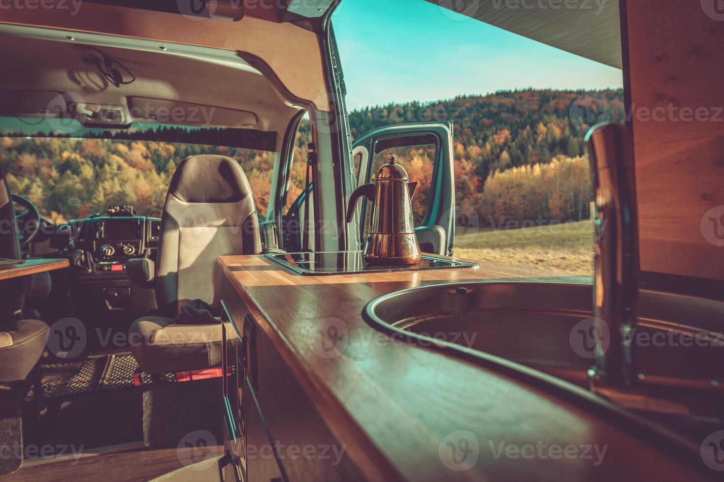 Cozy Interior of a Camper Van With a Kettle and Beautiful Forest View in the Daytime photo