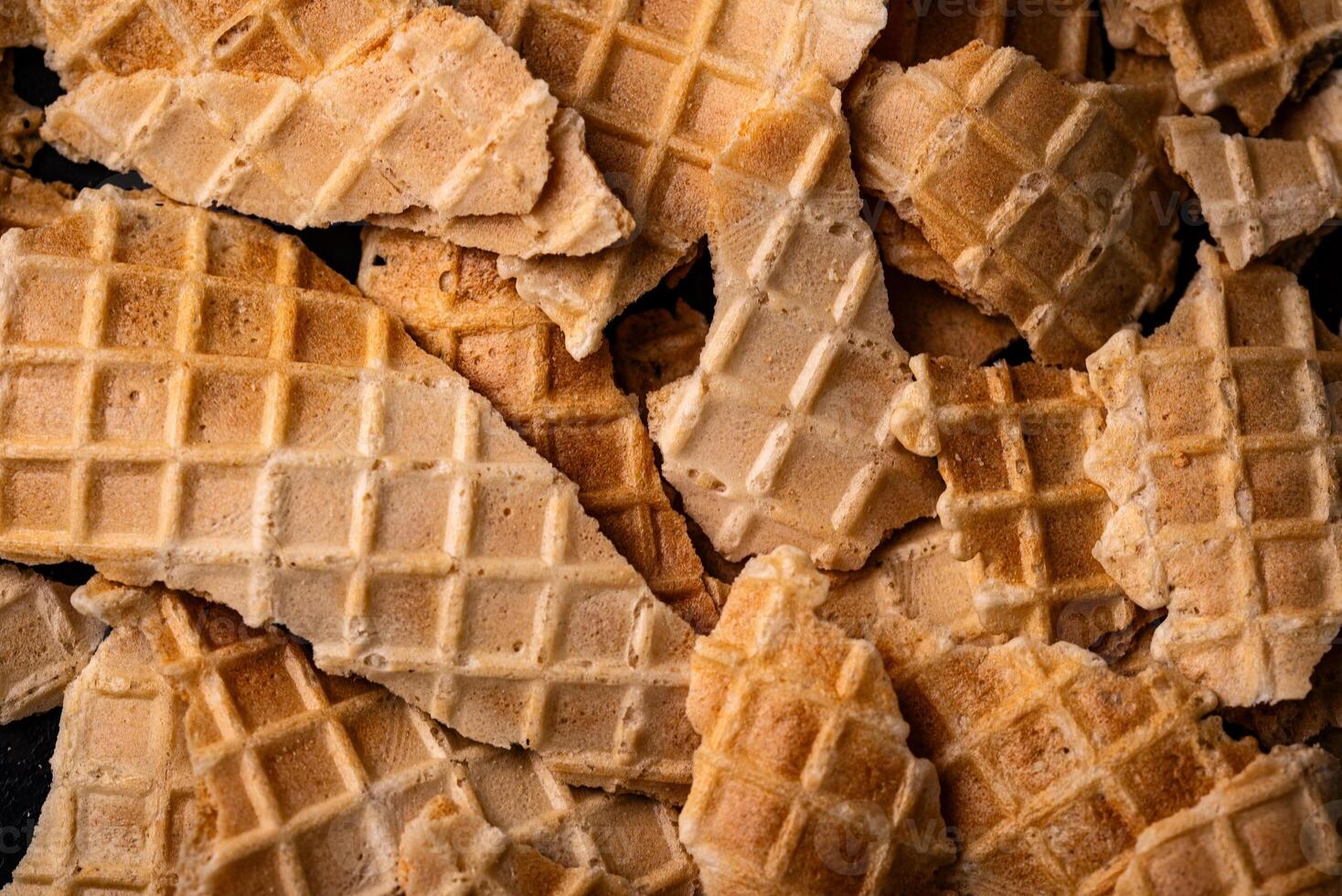Broken waffles on dark background texture photo