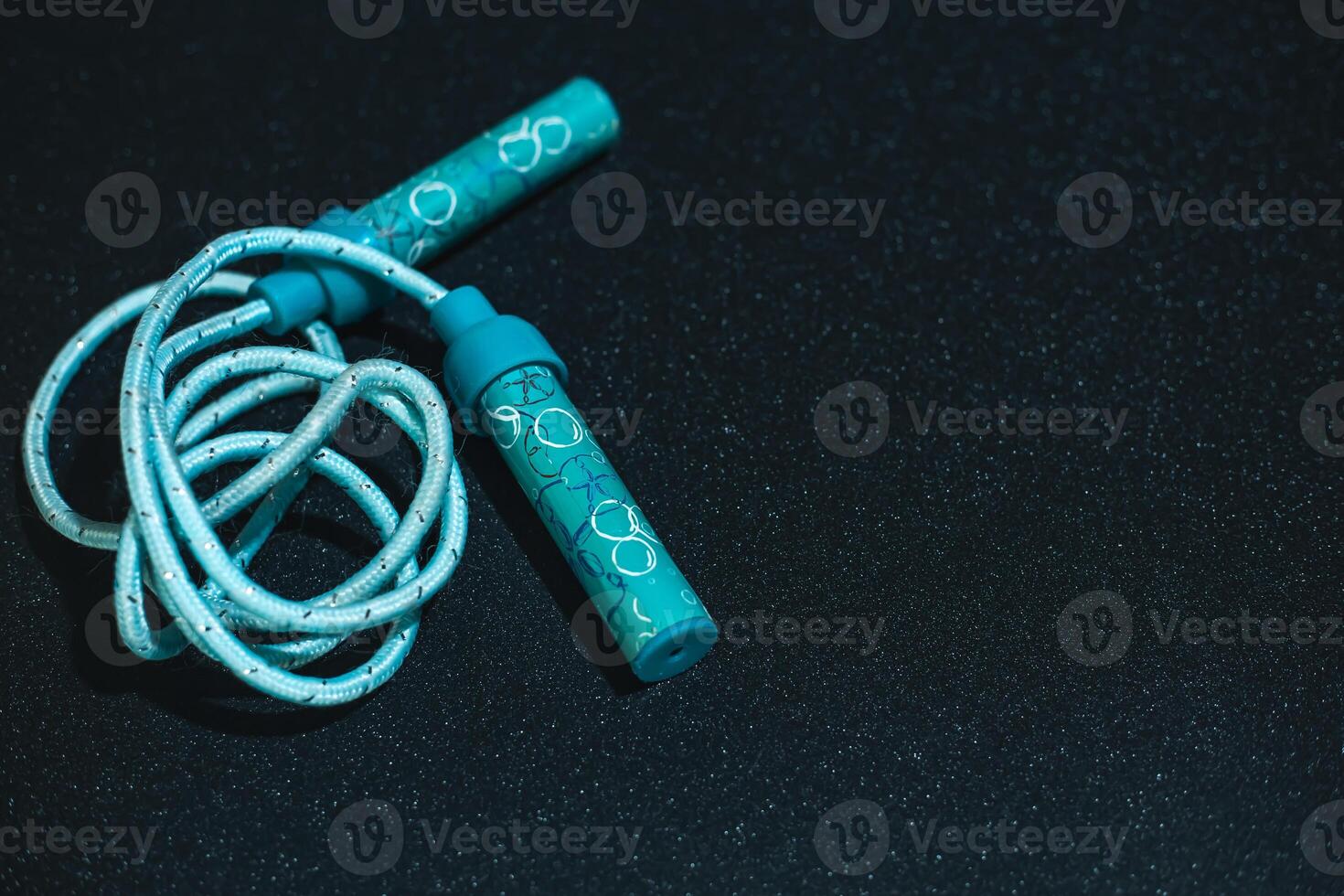 Sports Jumping rope on a black background. Blue children's jump rope on a black shiny background. Fitness concept. Banner photo