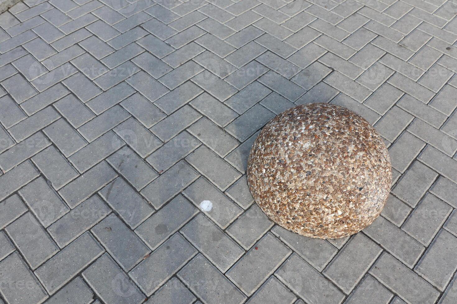 An Artistic and Abstract Representation of a Round Stone Placed on a Paved Surface photo