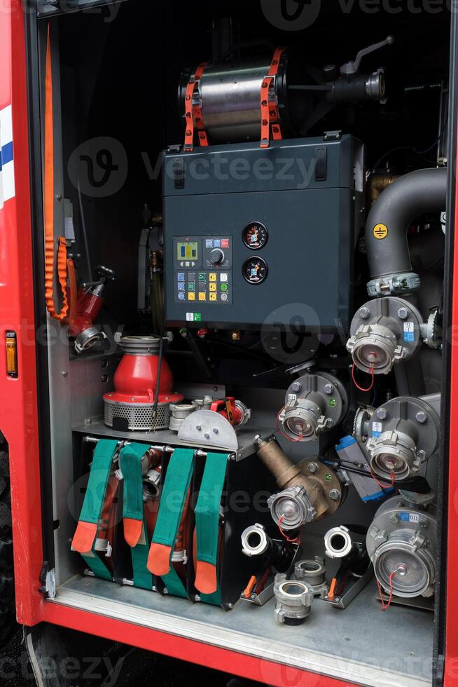 Fire truck equipment compartment showcasing tools and machinery for emergency response located at a fire station during daytime hours. photo