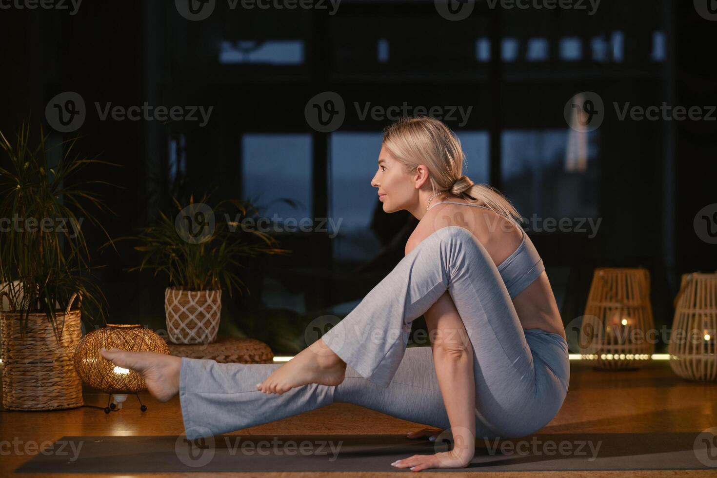 Dynamic yoga practice showcasing a woman performing an advanced pose in a serene and well-lit indoor studio environment during a peaceful evening session. photo
