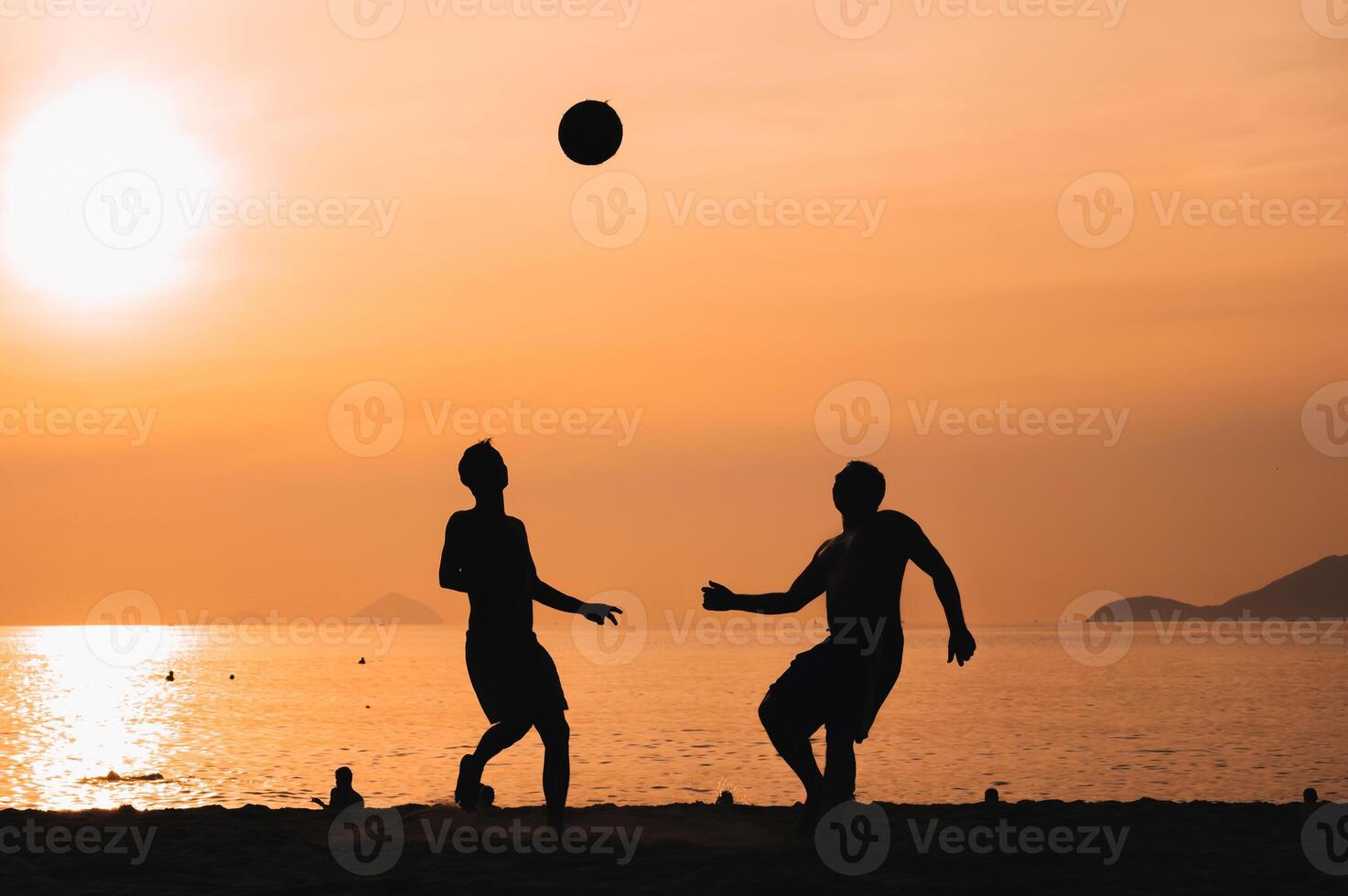 Silhouettes of Asian men playing beach soccer on beach at sunrise photo