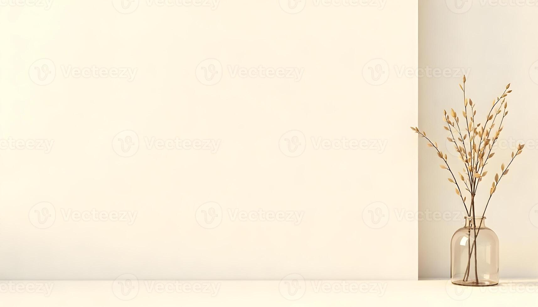 A minimalist arrangement featuring a glass vase holding dried branches against a soft, beige backdrop. photo