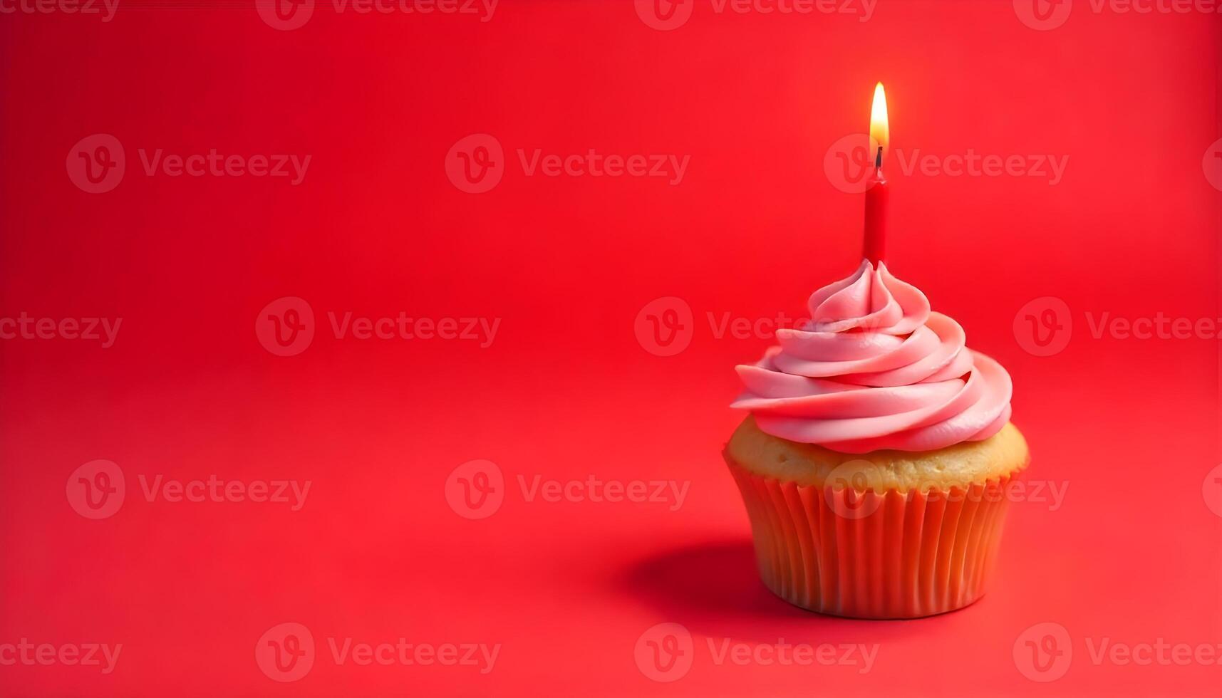 A beautifully decorated cupcake with pink frosting and a lit candle on a red background. photo