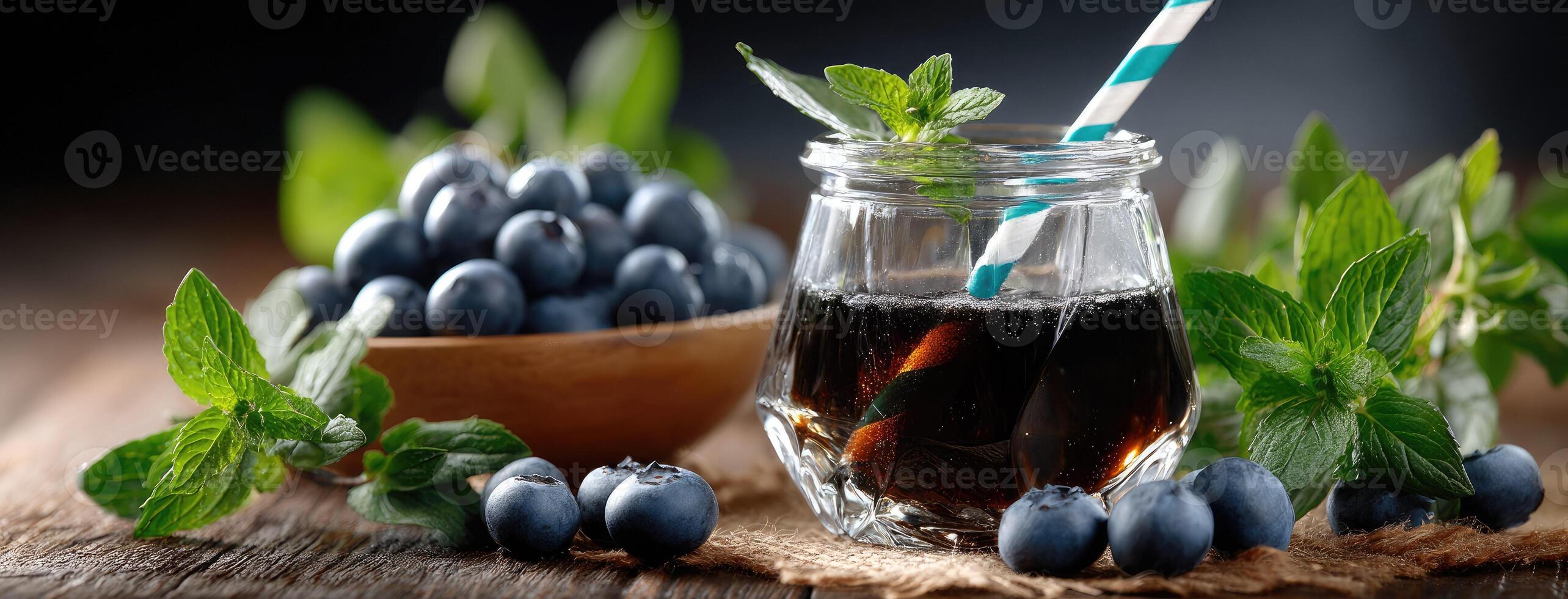 Blueberry juice in glass jar with straw and berries on wooden table photo