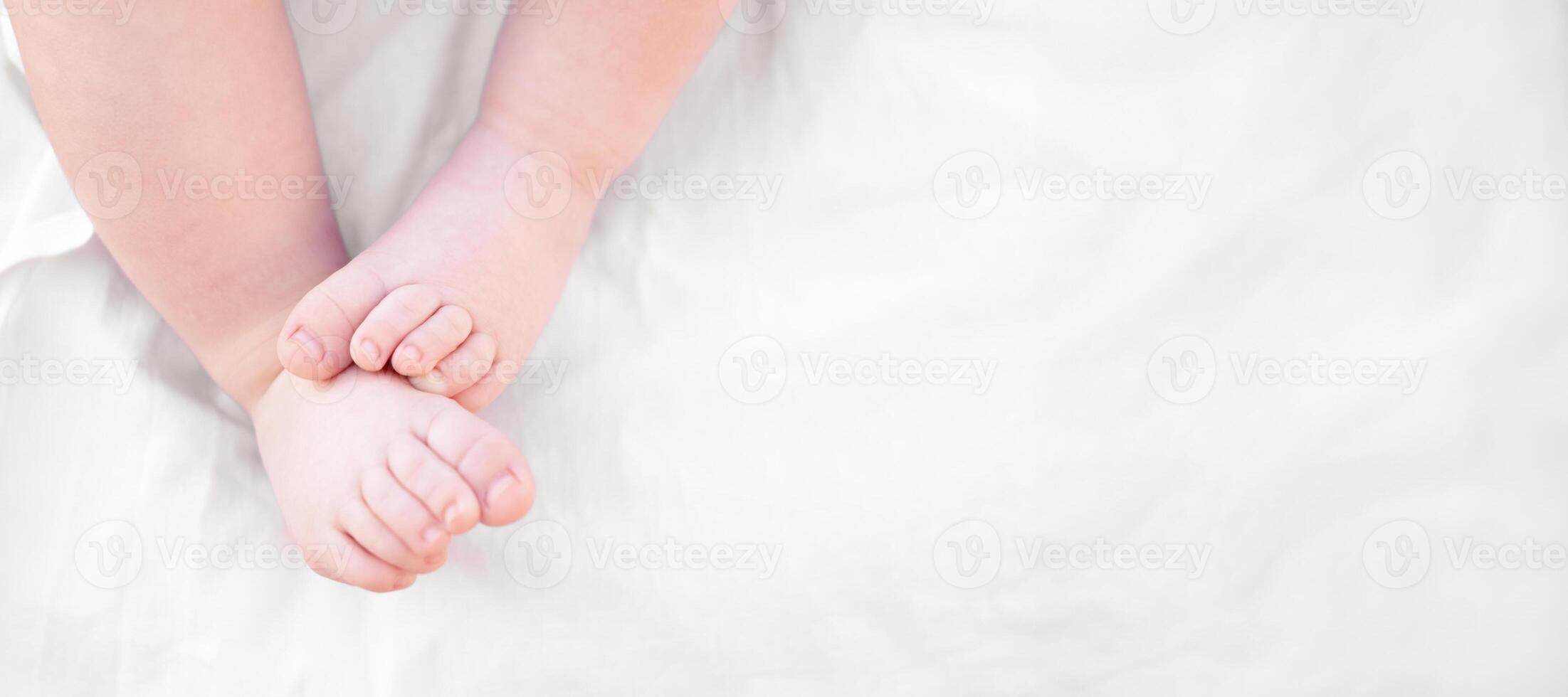 Legs close-up of newborn baby on light background, banner photo