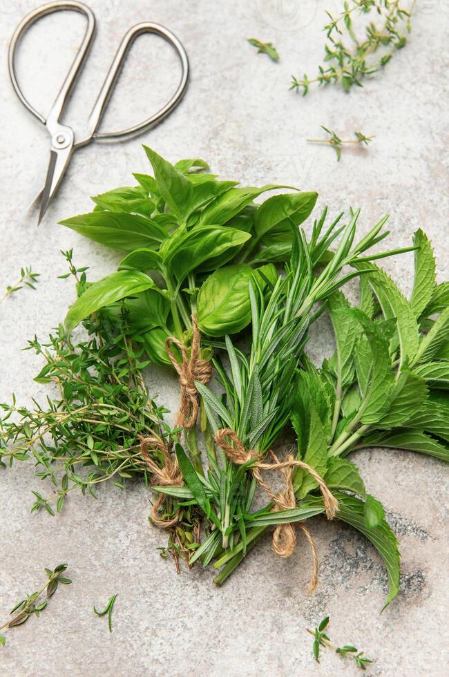 Freshly herbs tied with twine lying on gray marble with scissors photo