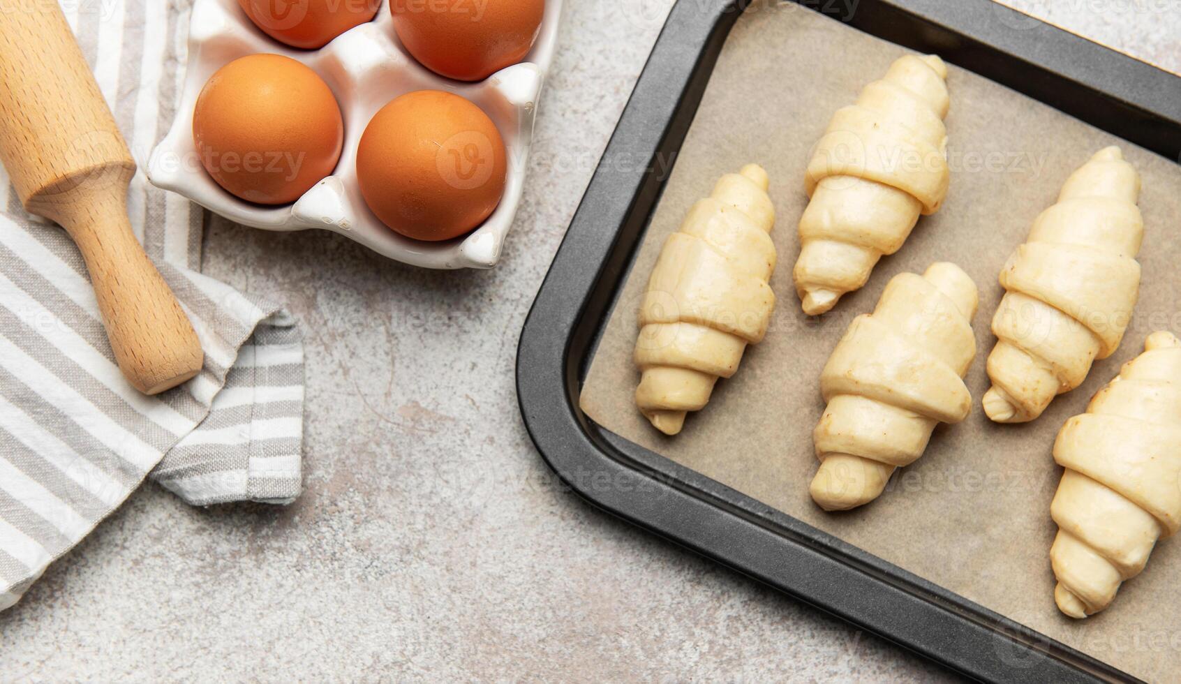 Freshly made croissants resting on baking sheet await oven's warm embrace photo