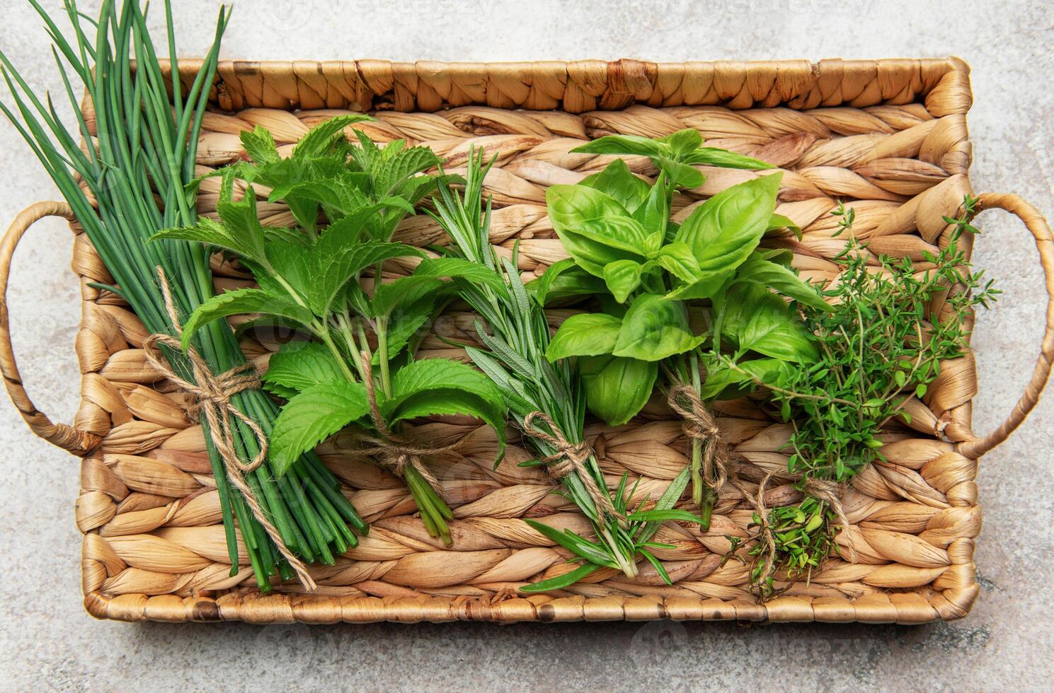 Fresh herbs tied in bundles resting on a woven tray photo
