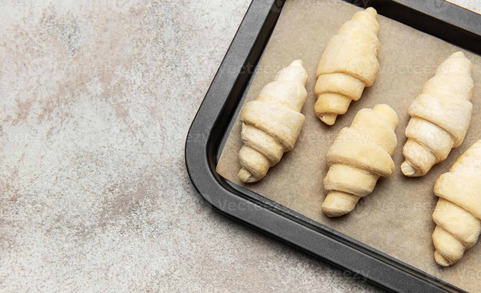 Raw croissant resting on baking sheet awaiting oven's warmth photo