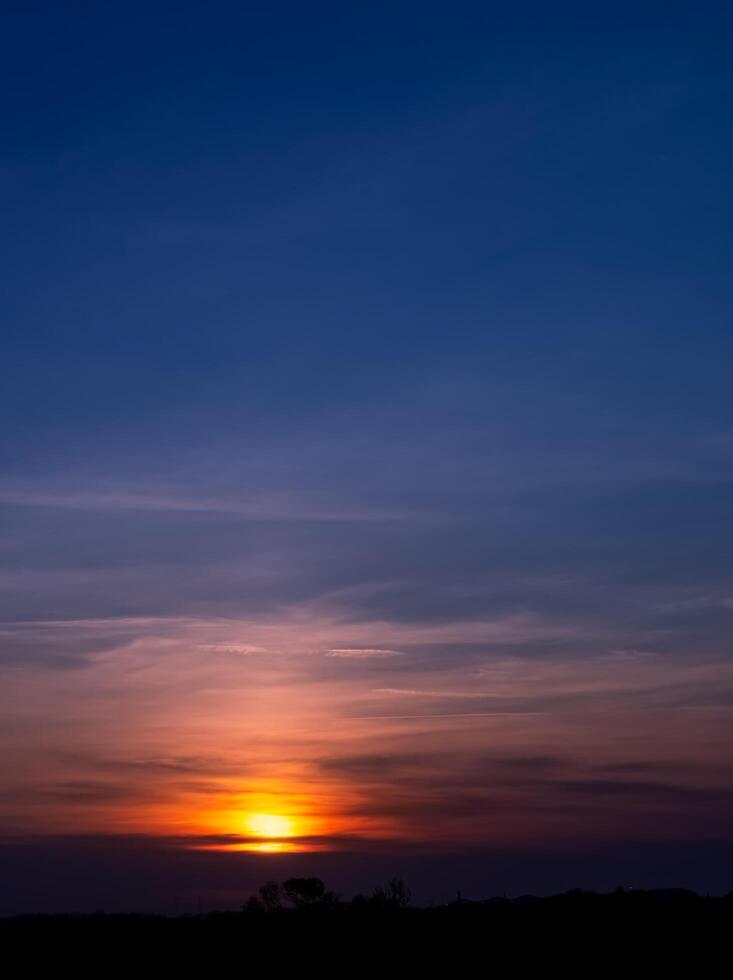 Sunset sky and dramatic clouds in evening Summer,Nature background sunrise reflection over forest trees in morning Spring,Vertical beautiful golden hour with twilight, dusk sky while sundown in Winter photo