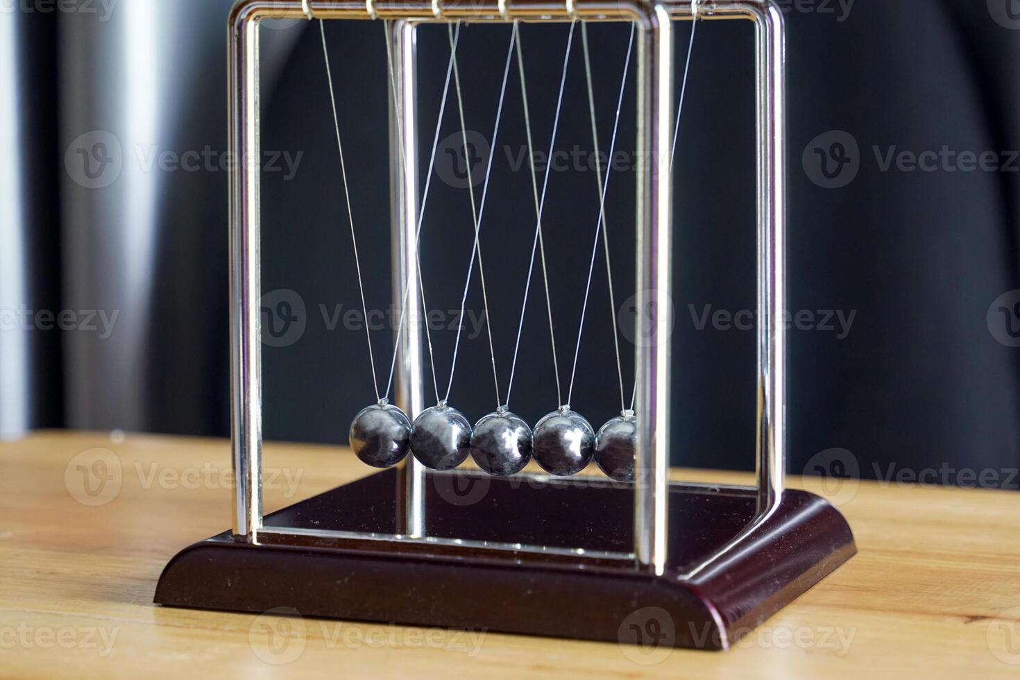 the Newtons cradle is a device that demonstrates the conservation of momentum and the conservation of energy with swinging spheres. Soft and selective focus. photo
