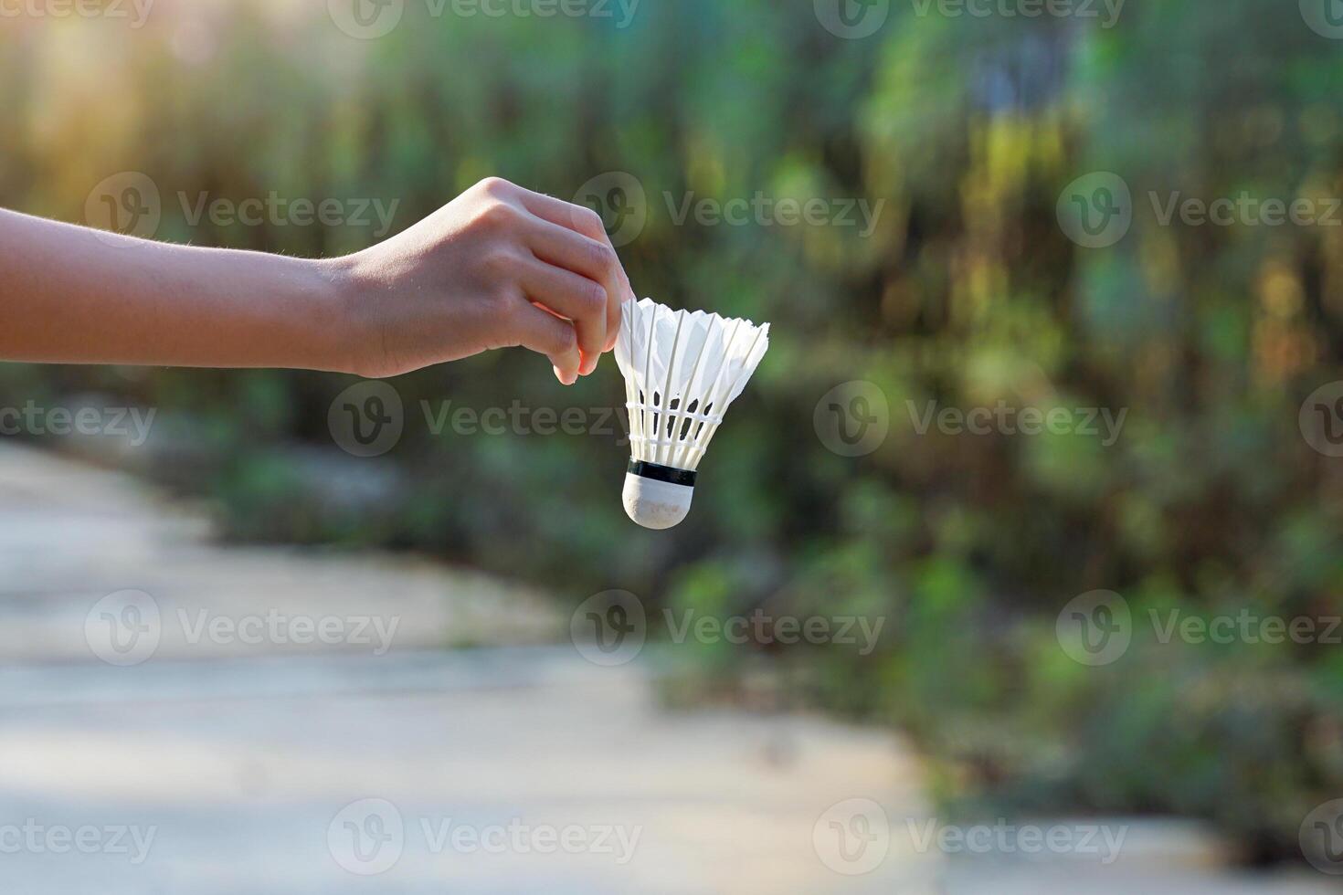 Hand holding a shuttlecock, concept for outdoor badminton playing in free times, soft and selective focus. photo