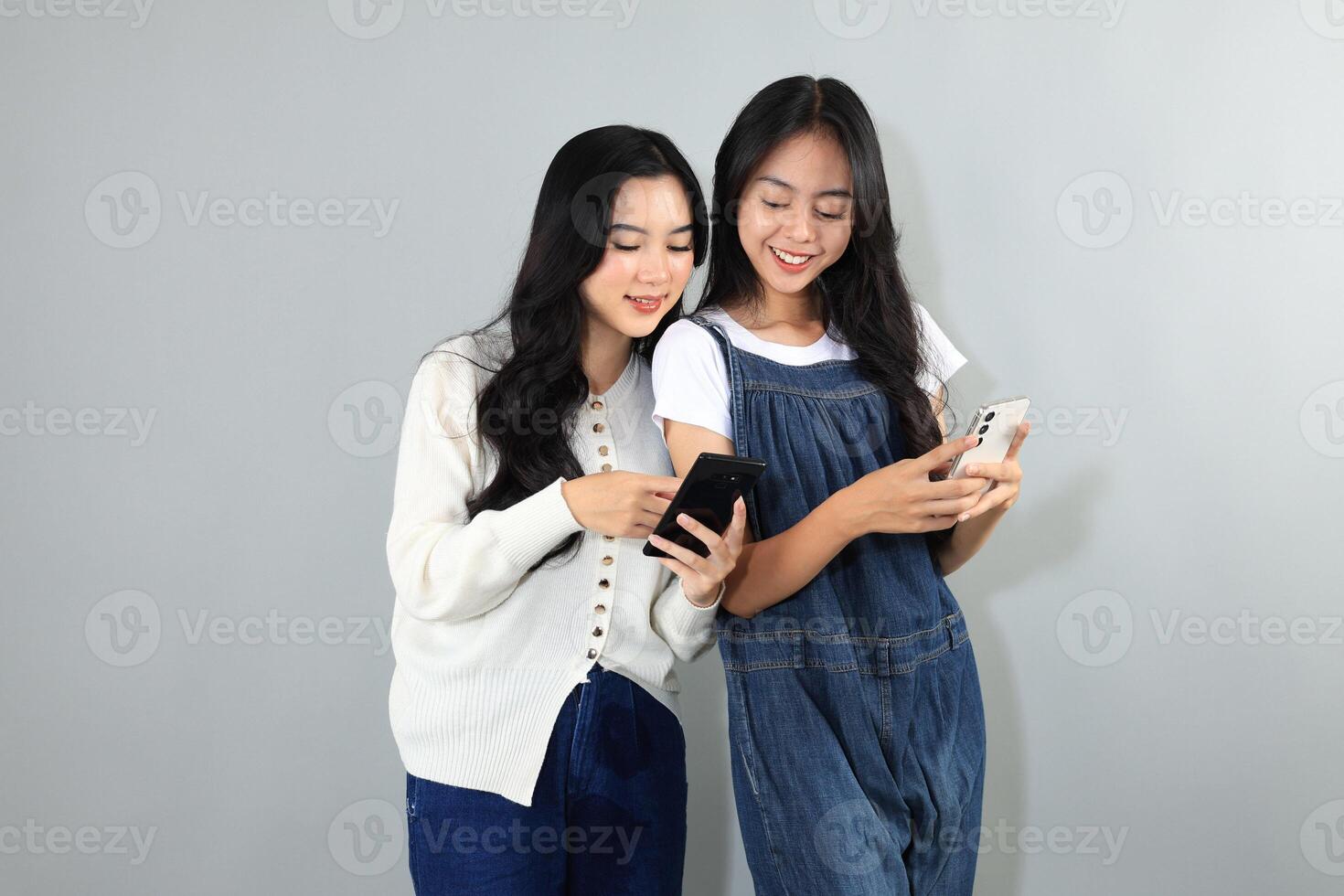 Two Asian Young Woman Holding Mobile Phone, Happy Bestfriend Interacting. photo